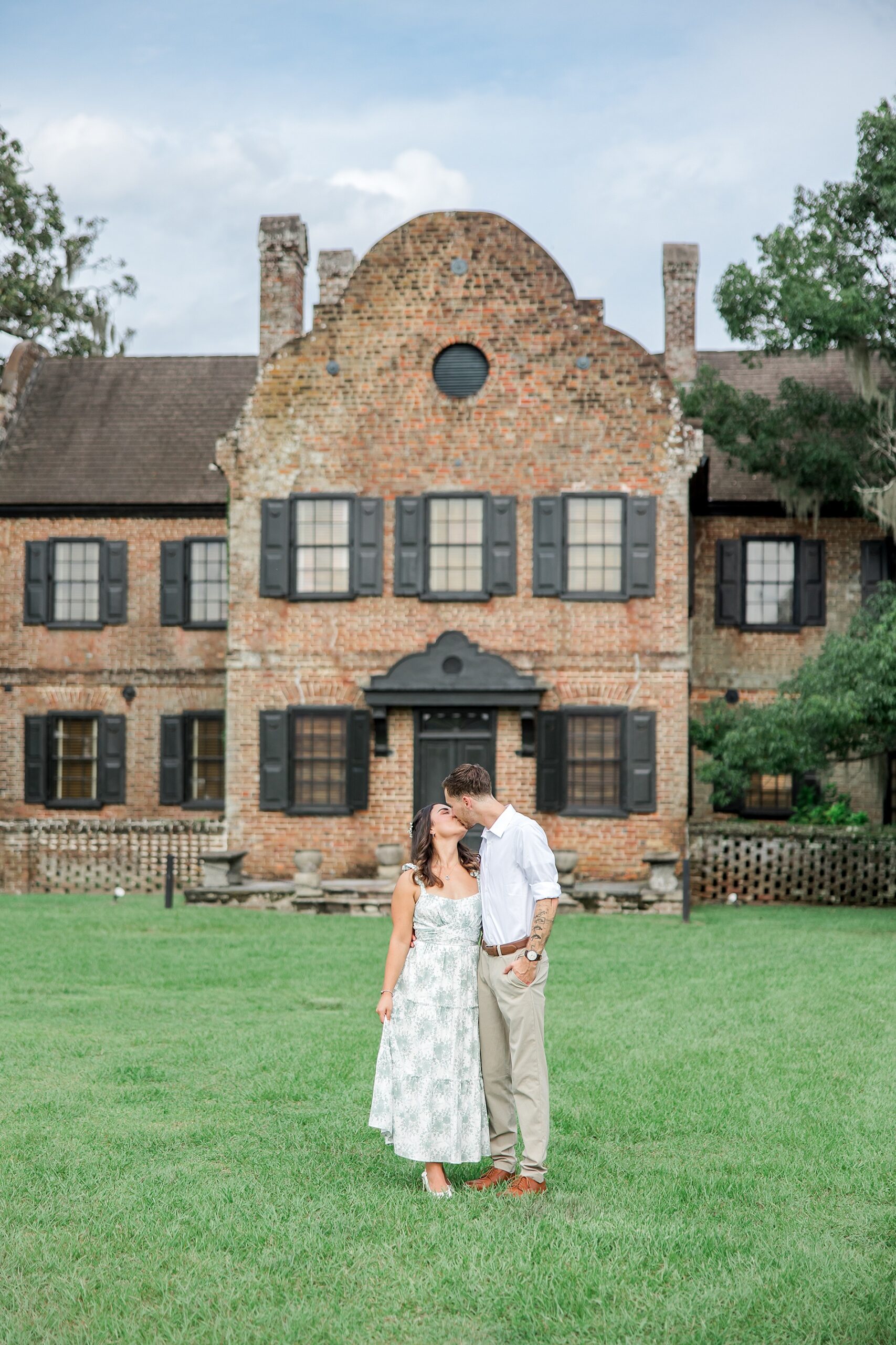 couple kiss in front of building at Middleton Place in Charleston